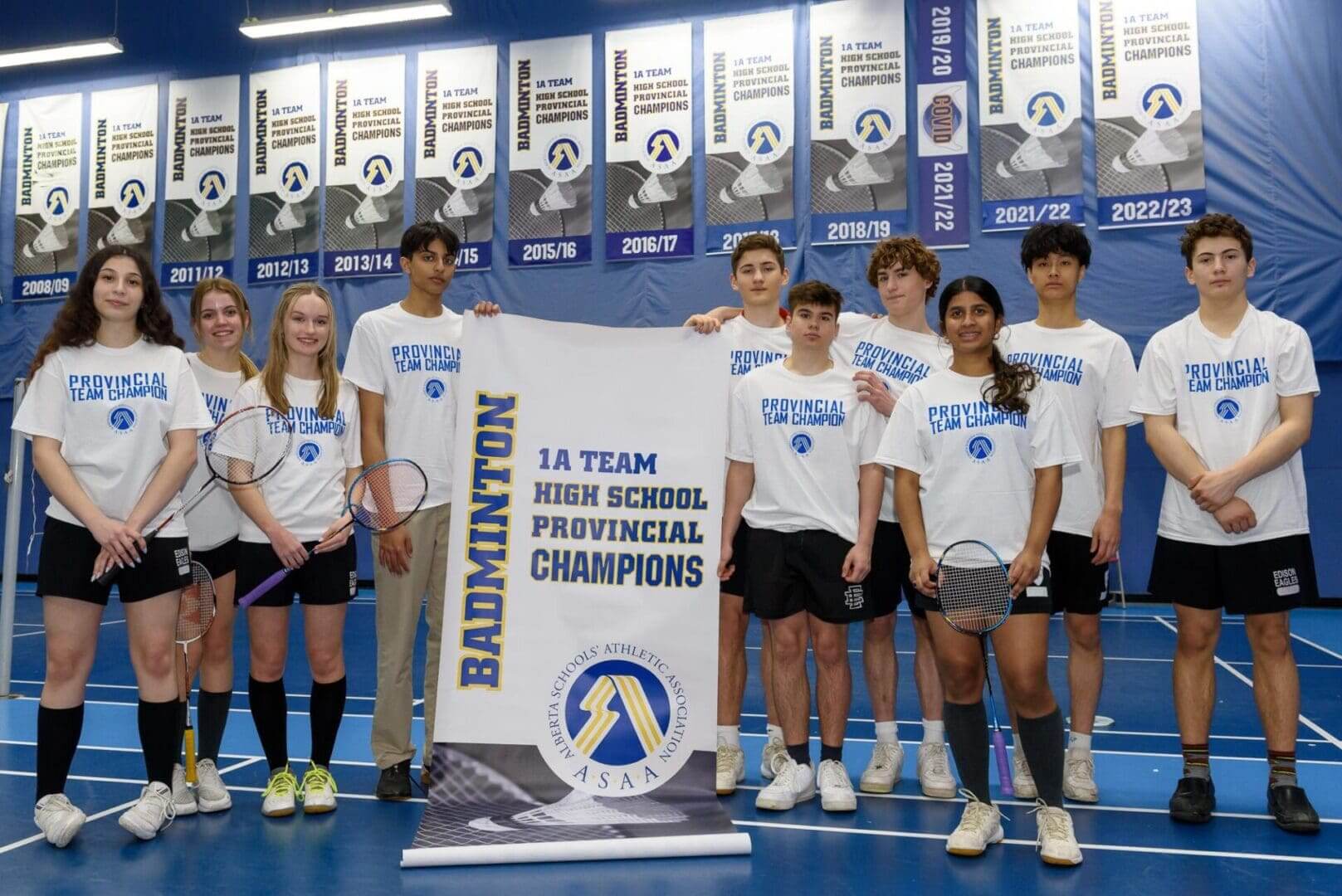 High school badminton team holding championship banner