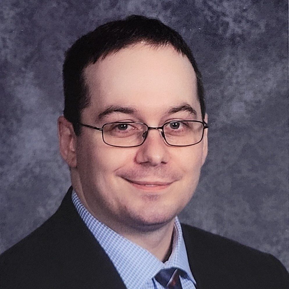 Headshot of man in glasses and suit.