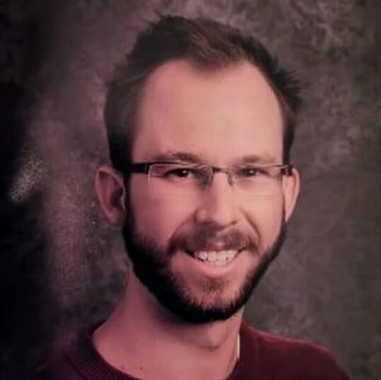 Headshot of a smiling man with glasses.
