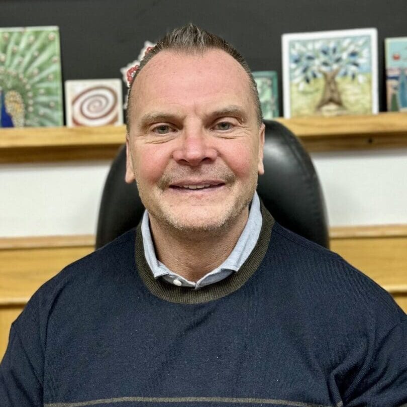 Smiling man with artwork on shelf