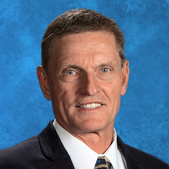 Here's an alt tag for the image: Headshot of a man in a suit.