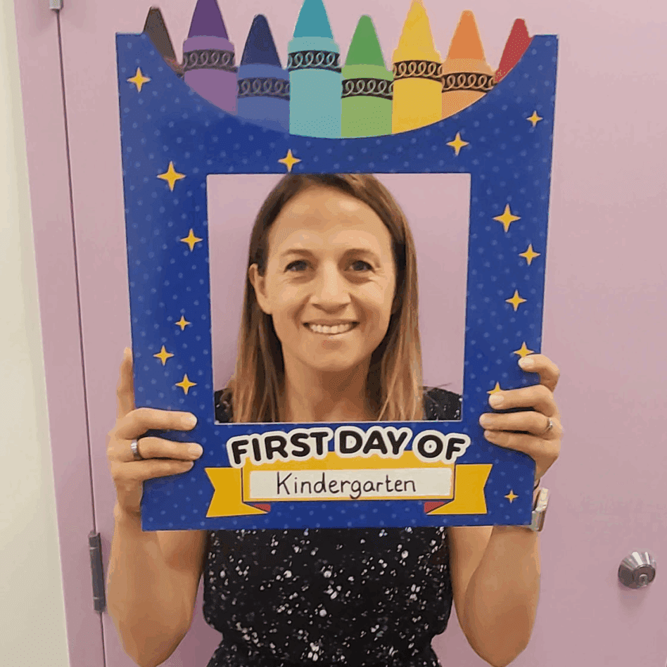 Smiling person holding "First Day of Kindergarten" frame